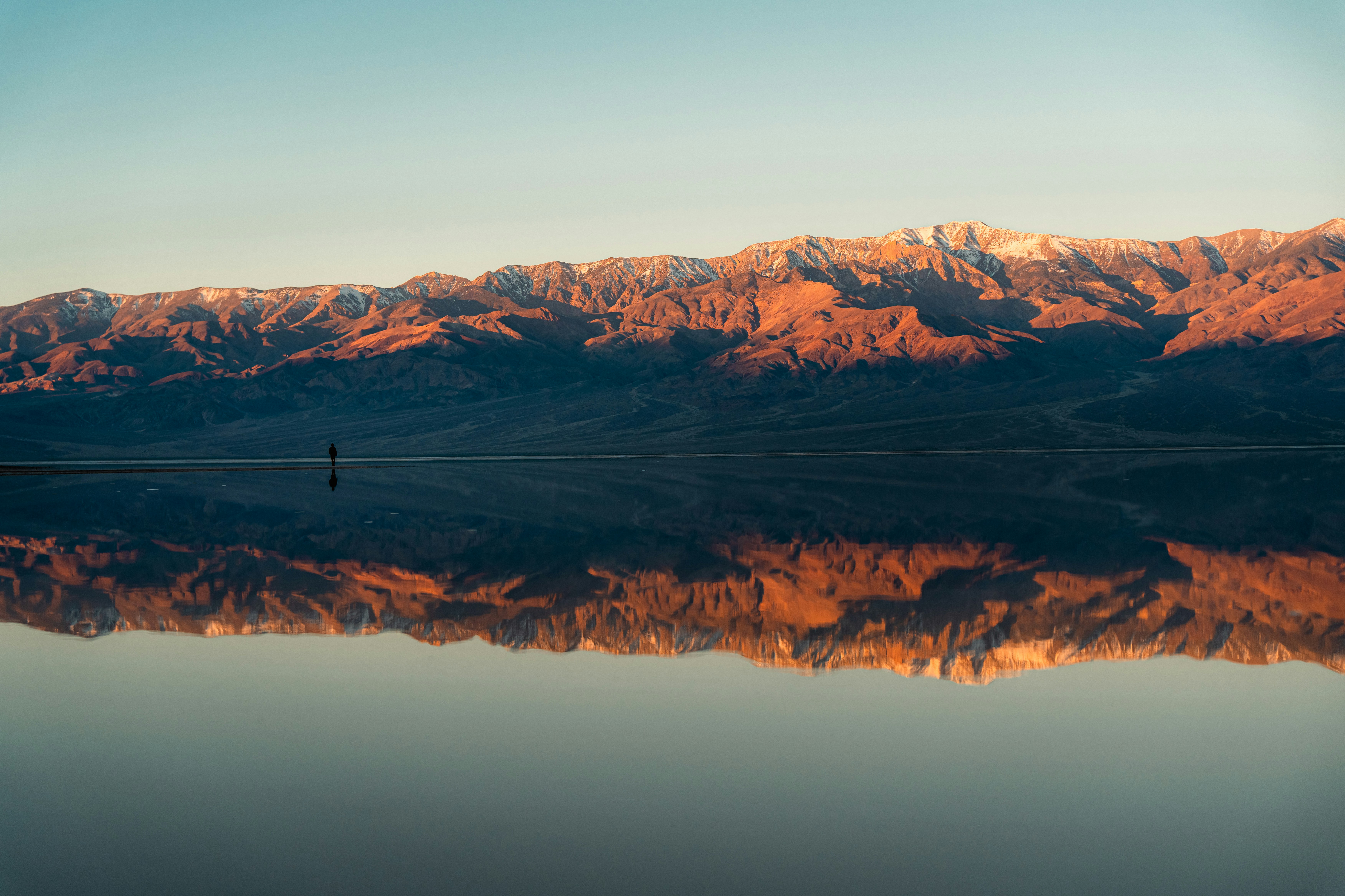 Snow-capped mountains reflecting in calm water at sunset